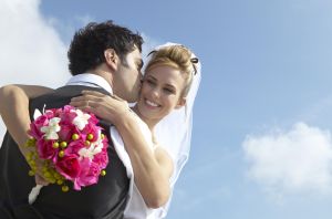 Newlywed Groom Kisses a Bride Holding a Bouquet on Her Cheek