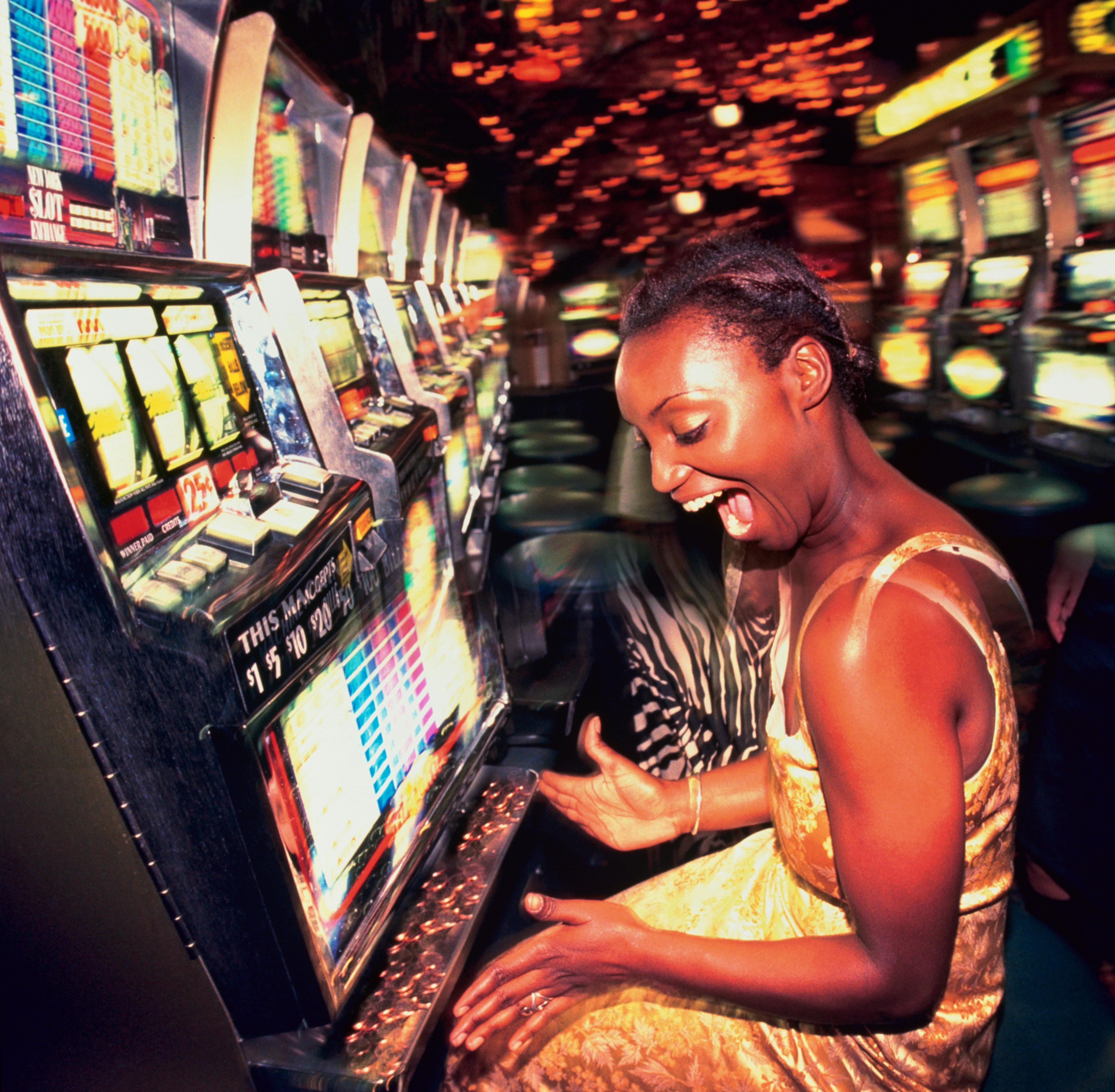 Young woman winning money from slot machine, profile