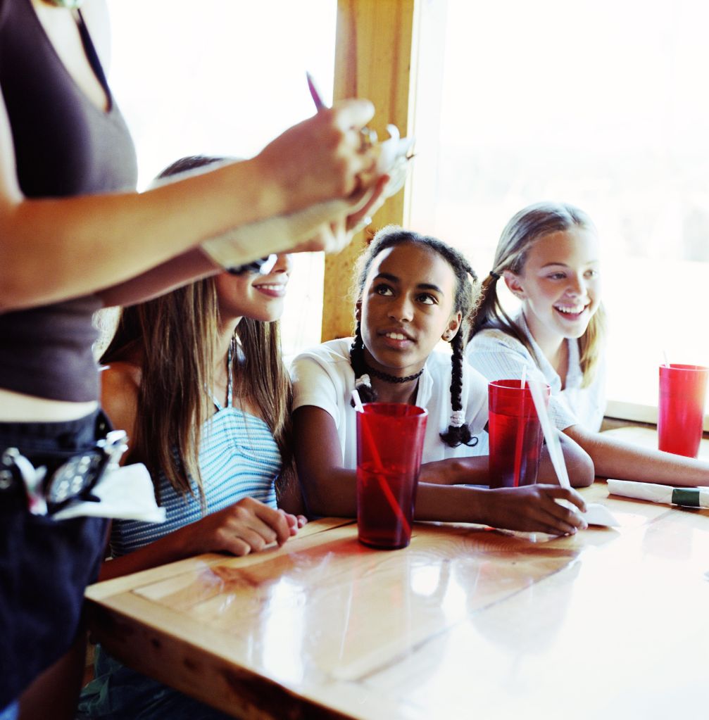 Teenage girls (14-16) giving waitress order in diner