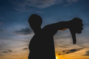 Silhouette Man Gesturing Thumbs Down Against Sky During Sunset