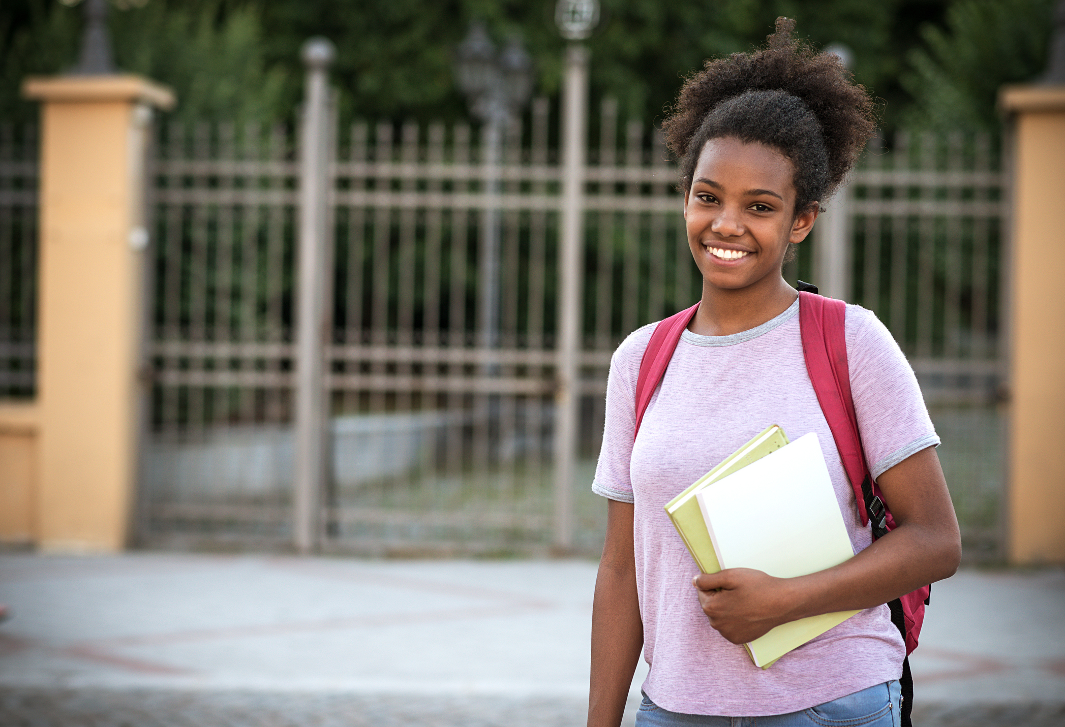 Teenage African girl with books going to school.