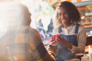 Boyfriend giving gift box to surprised girlfriend in cafe
