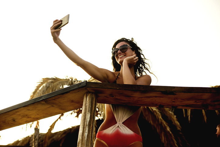 Beautiful young woman doing selfie on the beach