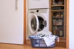 At home still life of full laundry basket with washing machine and dryer in the background