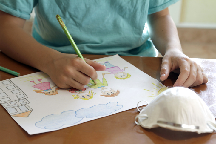 Boy painting family with protective masks during pandemic