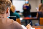 High School Students and Teacher wearing face masks and social distancing in Classroom Setting working on laptop technology