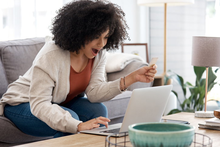 Shot of a young woman shopping online while sitting on the couch at home