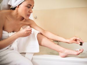 Shot of a young woman applying nail polish to her toenails after a bath